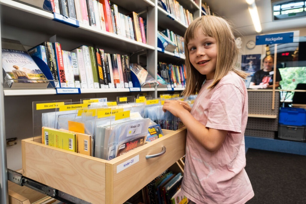 Ein Kind stöbert in der Bücherkiste.