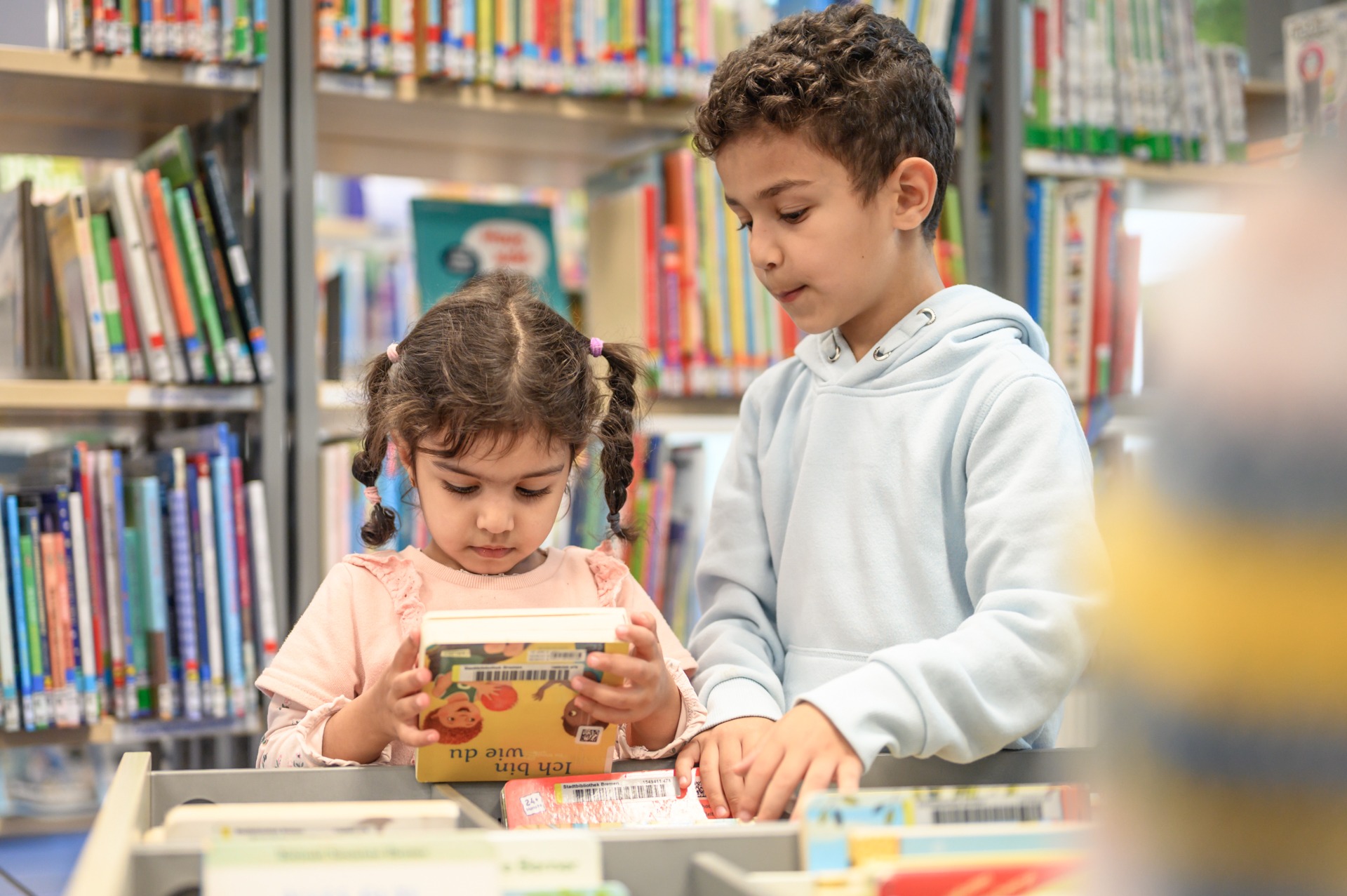 Zwei Kinder an einer Bücherkiste in der Bibliothek