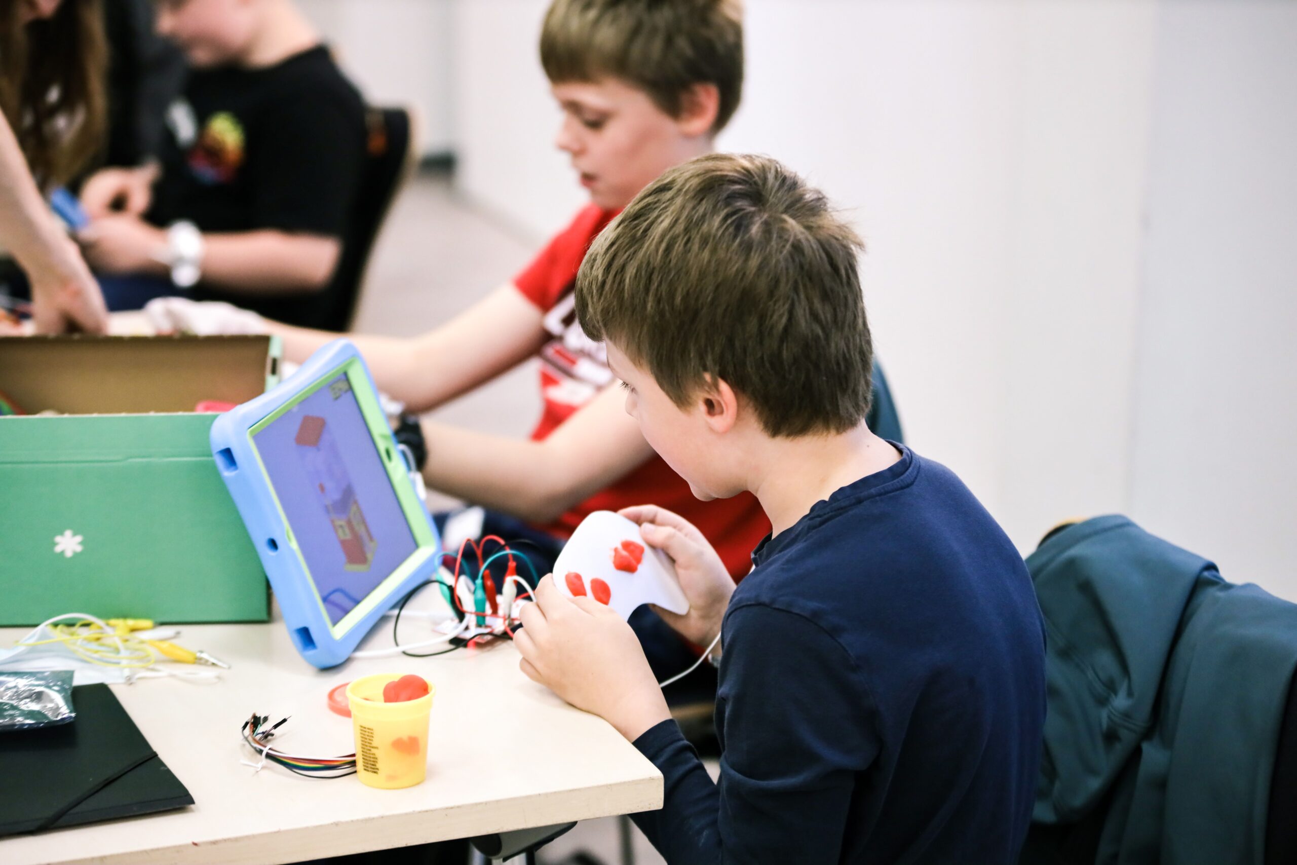 Das Foto zeigt zwei Jungen, die mit ihrem selbstgebauten Game-Controller ein Spiel spielen.