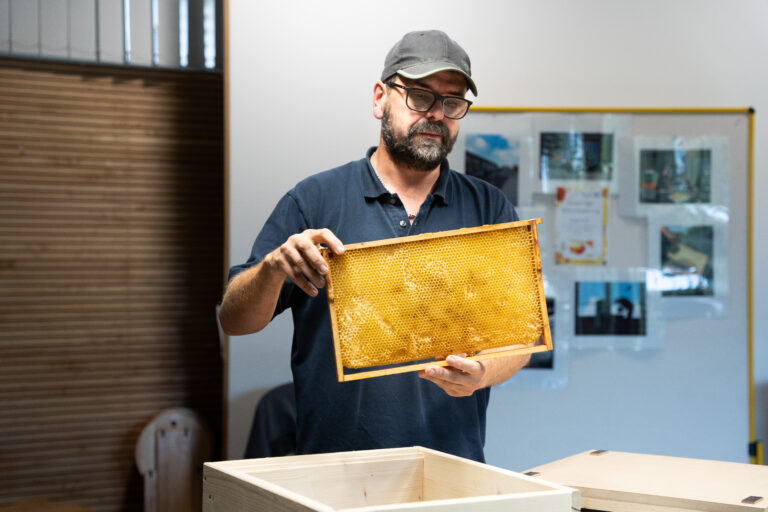A beekeeper with a honeycomb in his hand.