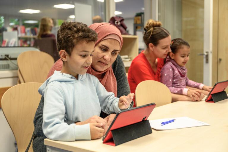 Mères avec enfants sur iPad dans la bibliothèque