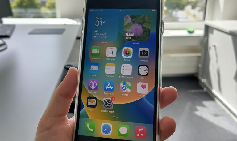 Изображението показва ръка, която държи смартфон с различни приложения на екрана.